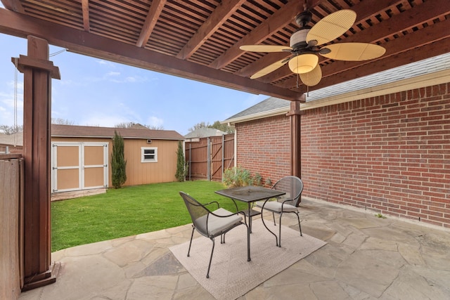 view of patio featuring a ceiling fan, an outbuilding, fence, a shed, and outdoor dining space