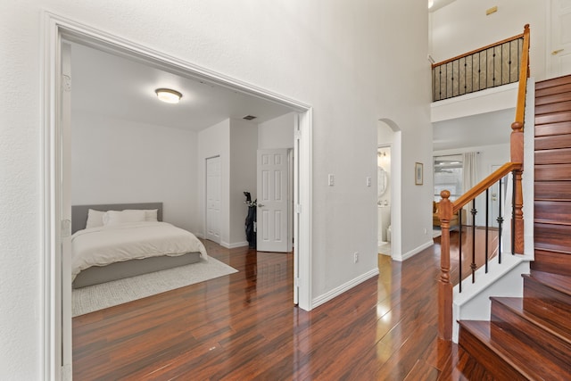 bedroom featuring arched walkways, wood finished floors, visible vents, and baseboards