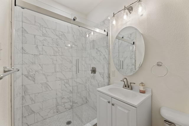 bathroom featuring toilet, a textured wall, a stall shower, and vanity