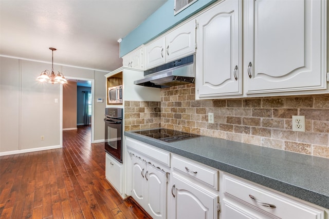 kitchen with dark countertops, under cabinet range hood, stovetop, and black oven