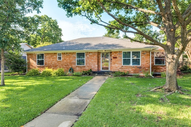 ranch-style home with a shingled roof, a front lawn, and brick siding