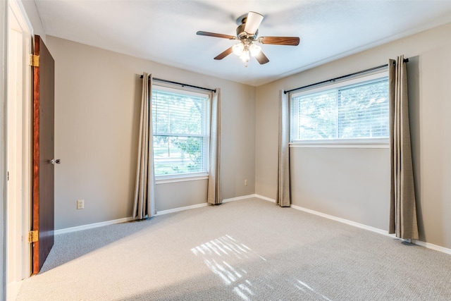 unfurnished room featuring a ceiling fan, light colored carpet, and baseboards