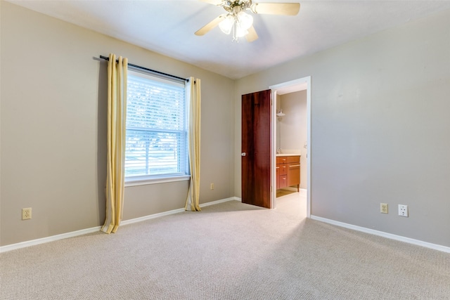 empty room featuring a ceiling fan, light colored carpet, and baseboards