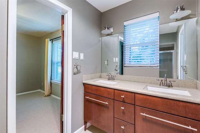 bathroom featuring a sink, a shower with shower door, and baseboards