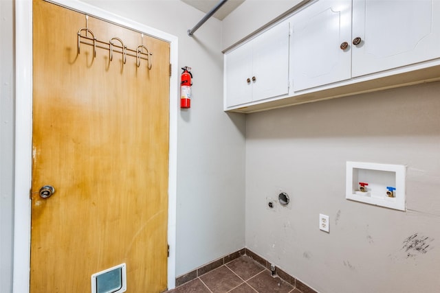 washroom featuring hookup for a washing machine, hookup for an electric dryer, dark tile patterned flooring, baseboards, and cabinet space