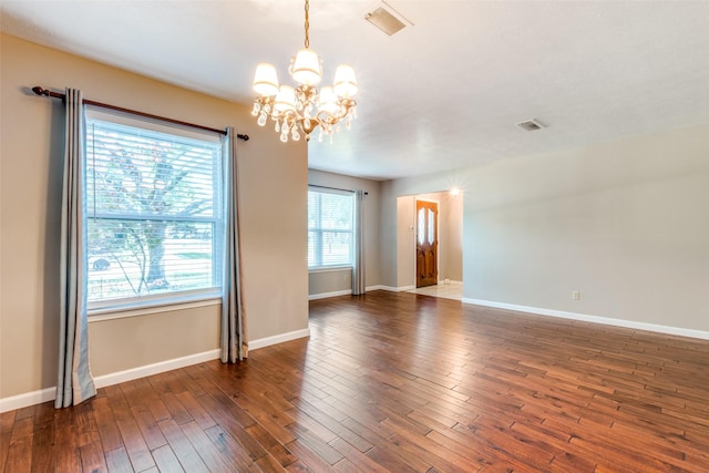 unfurnished room with visible vents, baseboards, a chandelier, and dark wood-type flooring