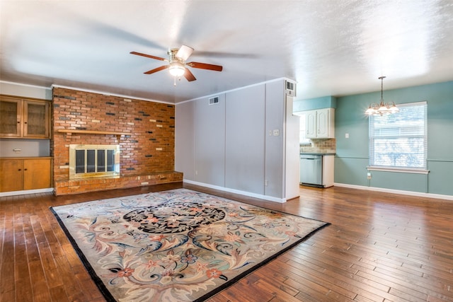 living area featuring ceiling fan with notable chandelier, a fireplace, dark wood finished floors, and visible vents