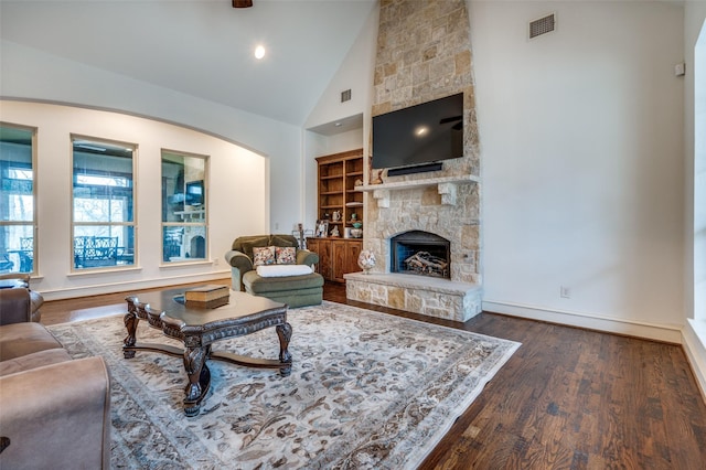 living area with high vaulted ceiling, a fireplace, wood finished floors, visible vents, and baseboards