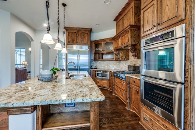 kitchen featuring stainless steel appliances, tasteful backsplash, a sink, and brown cabinets