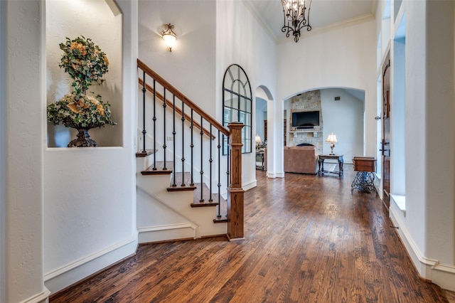 entrance foyer featuring arched walkways, a notable chandelier, crown molding, stairway, and hardwood / wood-style floors