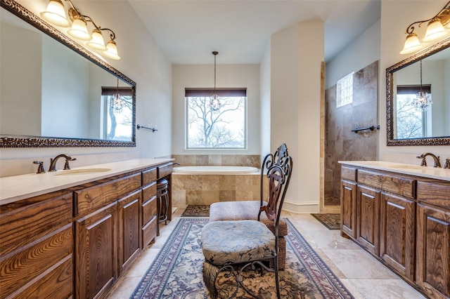 bathroom featuring a garden tub, two vanities, a sink, and a chandelier