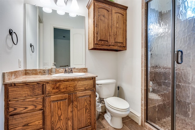 bathroom featuring toilet, vanity, baseboards, a shower stall, and tile patterned floors