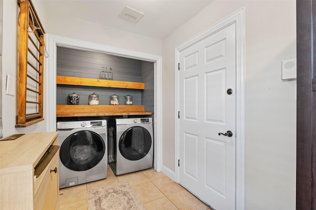 clothes washing area with laundry area, light tile patterned floors, and washing machine and clothes dryer