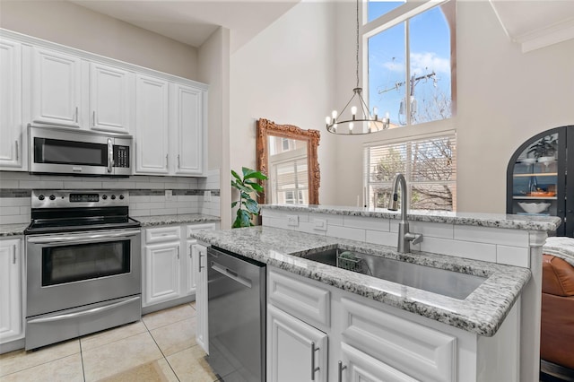 kitchen featuring light tile patterned flooring, a sink, white cabinets, appliances with stainless steel finishes, and tasteful backsplash