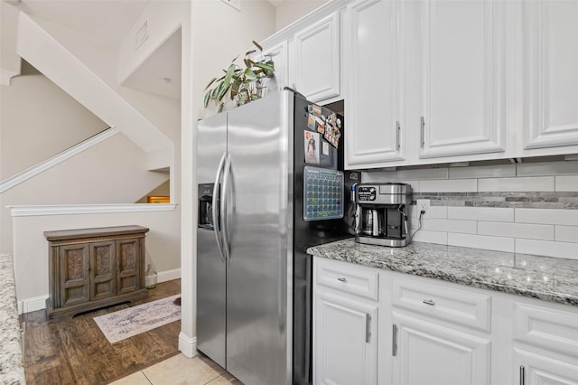 kitchen featuring tasteful backsplash, stainless steel fridge with ice dispenser, light stone countertops, light wood-style floors, and white cabinetry