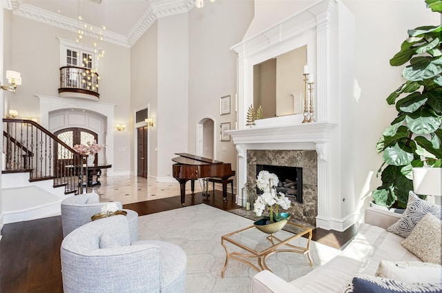 living area with wood finished floors, a premium fireplace, arched walkways, stairs, and a notable chandelier