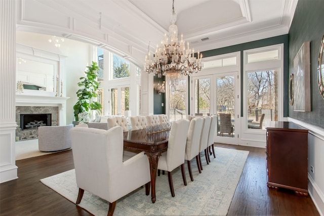 dining space with a high end fireplace, ornamental molding, french doors, wood finished floors, and a raised ceiling