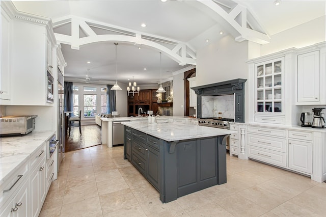 kitchen with gray cabinetry, white cabinetry, appliances with stainless steel finishes, a large island with sink, and vaulted ceiling