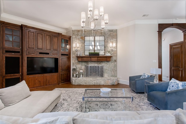 living area with arched walkways, a stone fireplace, ornamental molding, and wood finished floors