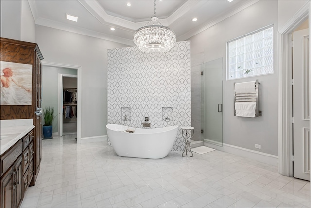 bathroom with a freestanding tub, ornamental molding, a shower stall, a raised ceiling, and a notable chandelier