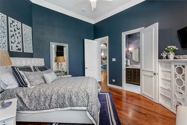 bedroom featuring connected bathroom, crown molding, baseboards, and wood finished floors