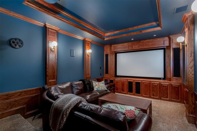 home theater room with a tray ceiling, crown molding, visible vents, and carpet floors