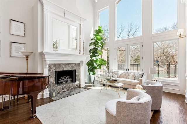 living area featuring a towering ceiling, dark wood-style floors, and a high end fireplace