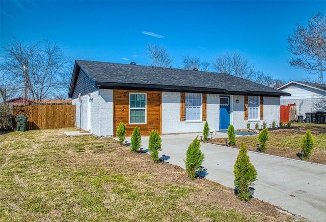 ranch-style home featuring brick siding, roof with shingles, fence, and a front yard