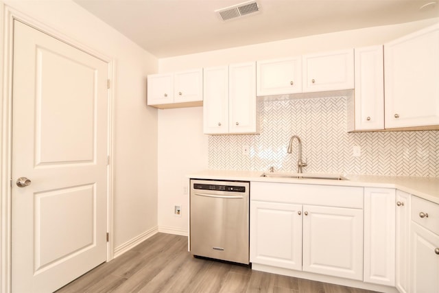 kitchen with stainless steel dishwasher, a sink, visible vents, and white cabinetry