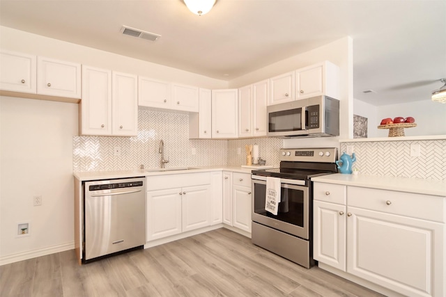 kitchen with visible vents, white cabinets, stainless steel appliances, light countertops, and a sink