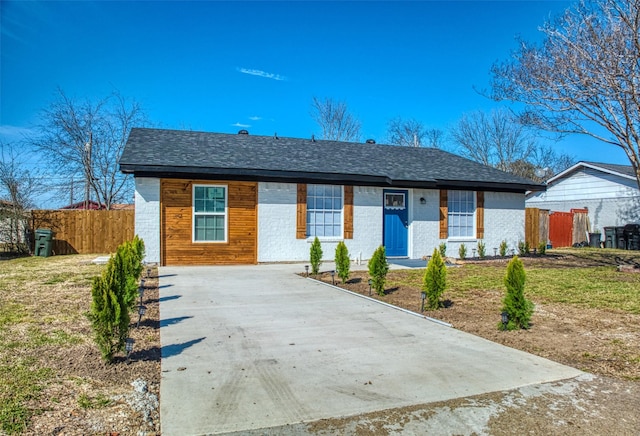 ranch-style home with brick siding, fence, and roof with shingles