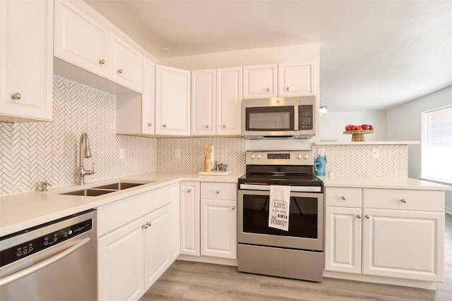 kitchen featuring stainless steel appliances, a sink, white cabinetry, light countertops, and tasteful backsplash