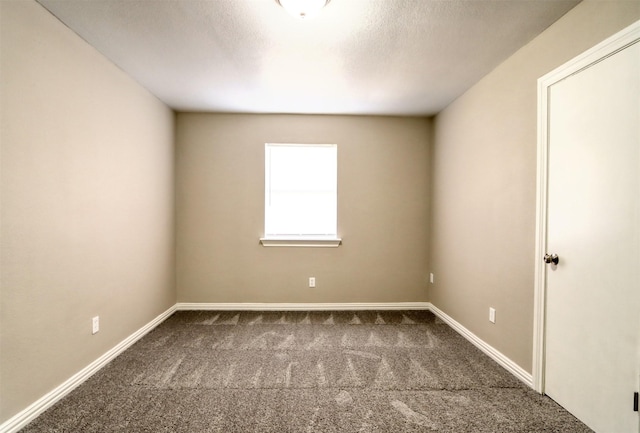 carpeted spare room featuring a textured ceiling and baseboards