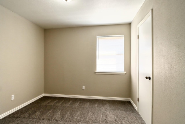 empty room featuring dark carpet and baseboards