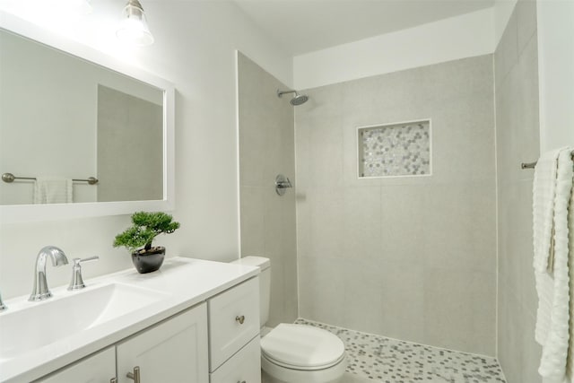 full bathroom with tiled shower, vanity, and toilet