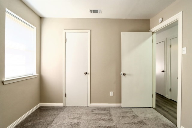 unfurnished bedroom featuring carpet floors, visible vents, and baseboards