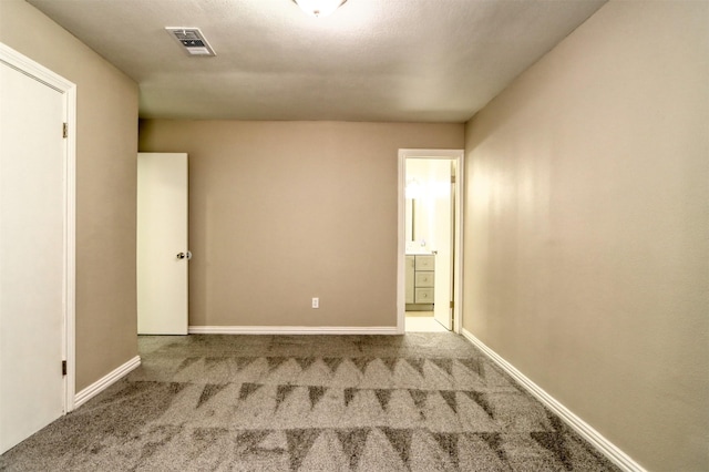 unfurnished room with carpet flooring, visible vents, and baseboards