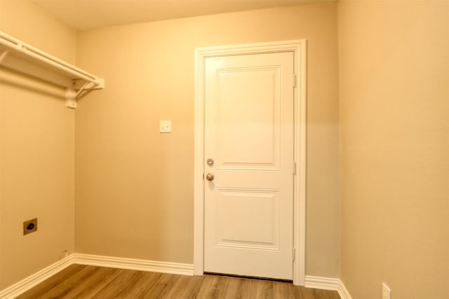 clothes washing area featuring laundry area, wood finished floors, electric dryer hookup, and baseboards