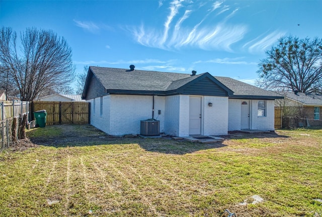 rear view of house with brick siding, a lawn, cooling unit, and a fenced backyard