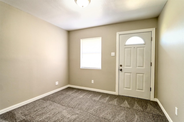 entryway with dark colored carpet and baseboards