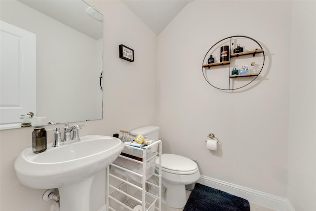 bathroom with lofted ceiling, baseboards, a sink, and toilet