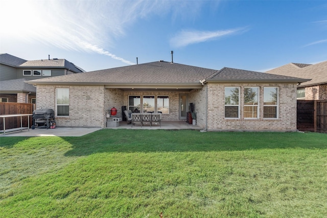 back of property with a patio area, a fenced backyard, a shingled roof, and a lawn