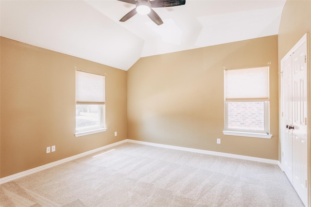 empty room with carpet floors, ceiling fan, baseboards, and vaulted ceiling