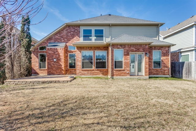 back of house with a shingled roof, fence, a yard, a patio area, and brick siding