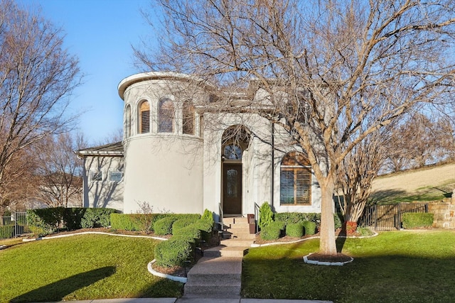 view of front facade with a front lawn, fence, a gate, and stucco siding