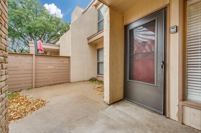 doorway to property with fence, a patio, and stucco siding