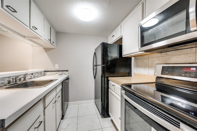 kitchen featuring light countertops, decorative backsplash, appliances with stainless steel finishes, white cabinets, and a sink