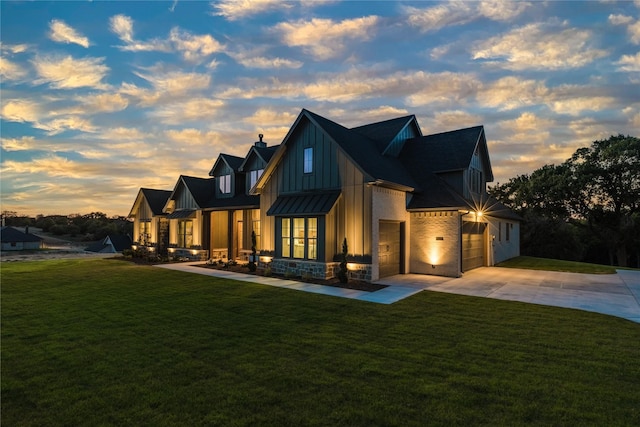 back of property featuring a standing seam roof, concrete driveway, a lawn, and metal roof