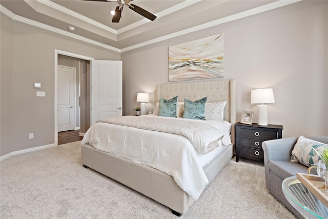 carpeted bedroom featuring a tray ceiling, crown molding, baseboards, and ceiling fan