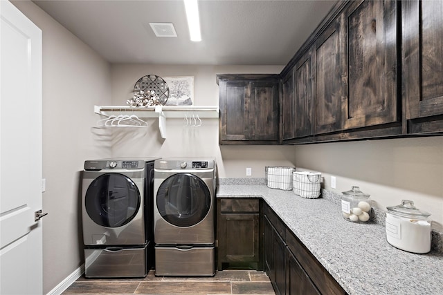 laundry area with wood finish floors, visible vents, baseboards, cabinet space, and washer and clothes dryer